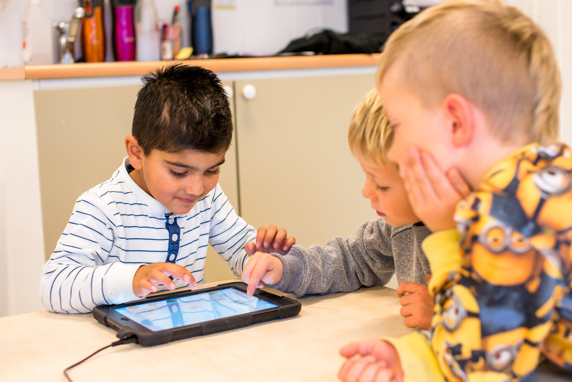 Tre barnehagegutter rundt et bord med iPad