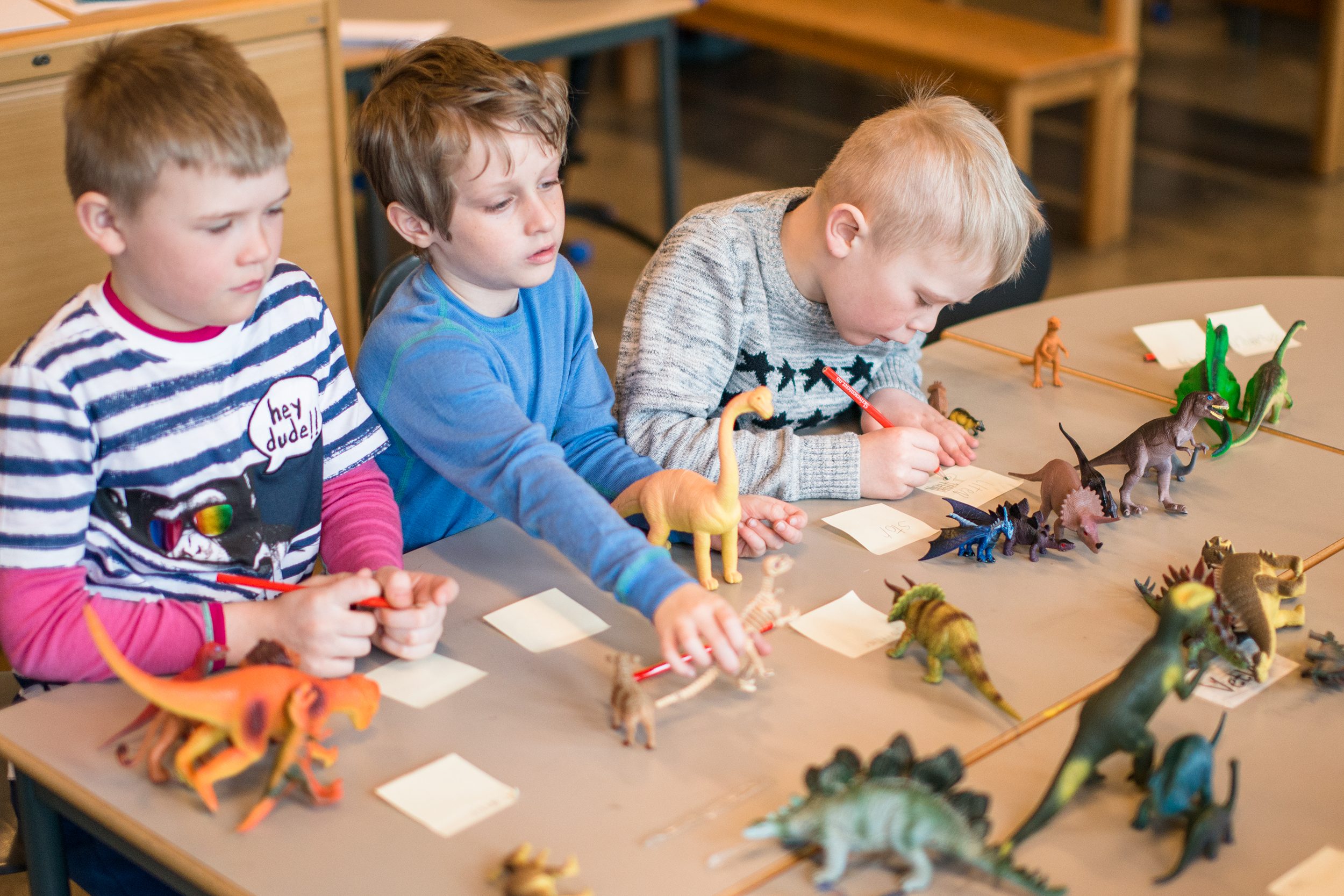 Tre gutter på barnetrinn som skriver om dinosaurer