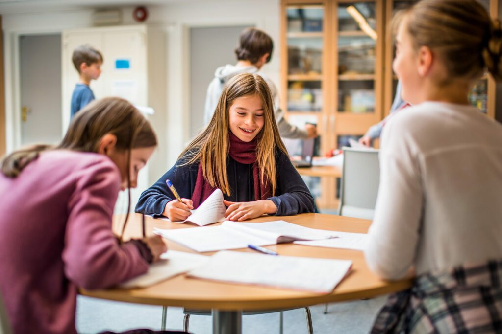 Tre elever på mellomtrinn / ungdomsskole som skriver og diskuterer