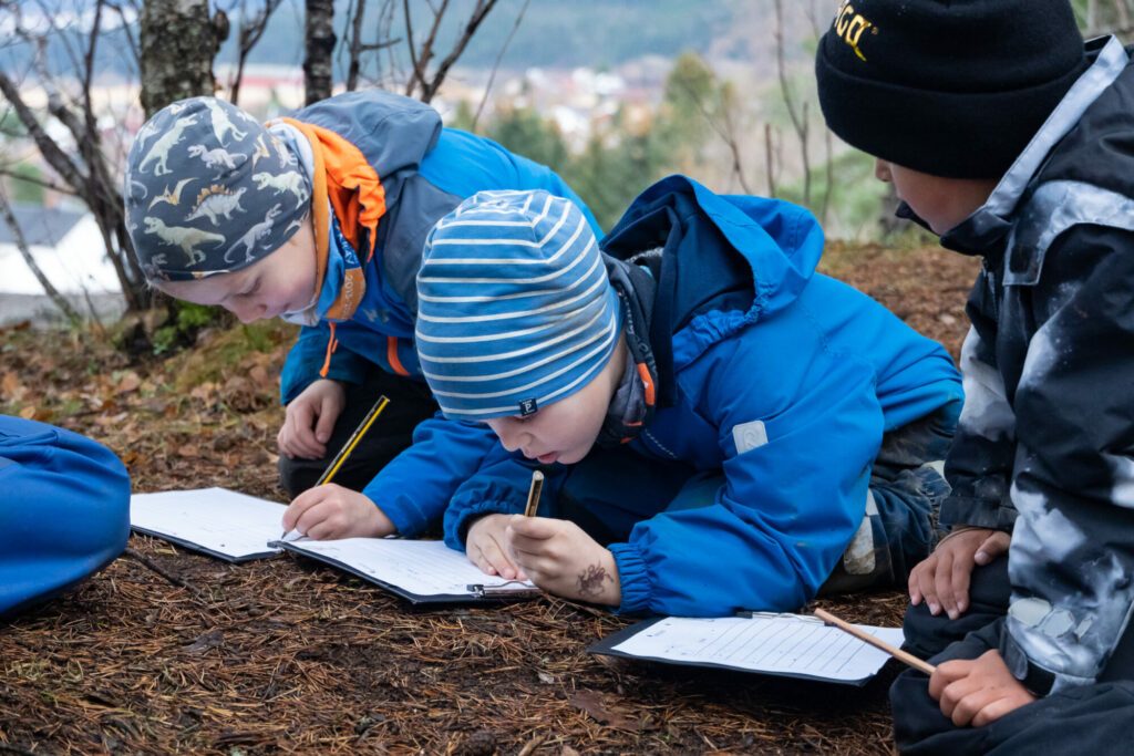 Elever skriver på uteskole på barneskole / begynneropplæring