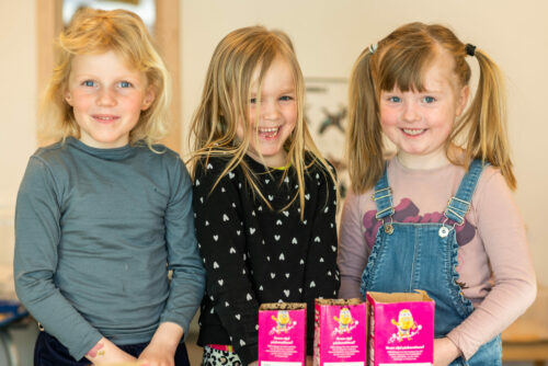 Tre jenter i barnehagen viser frem det de har plantet.