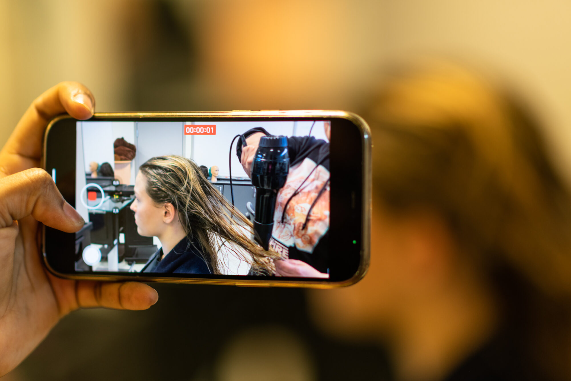 Mobilfilming på vgs frisør føner håret til elev.