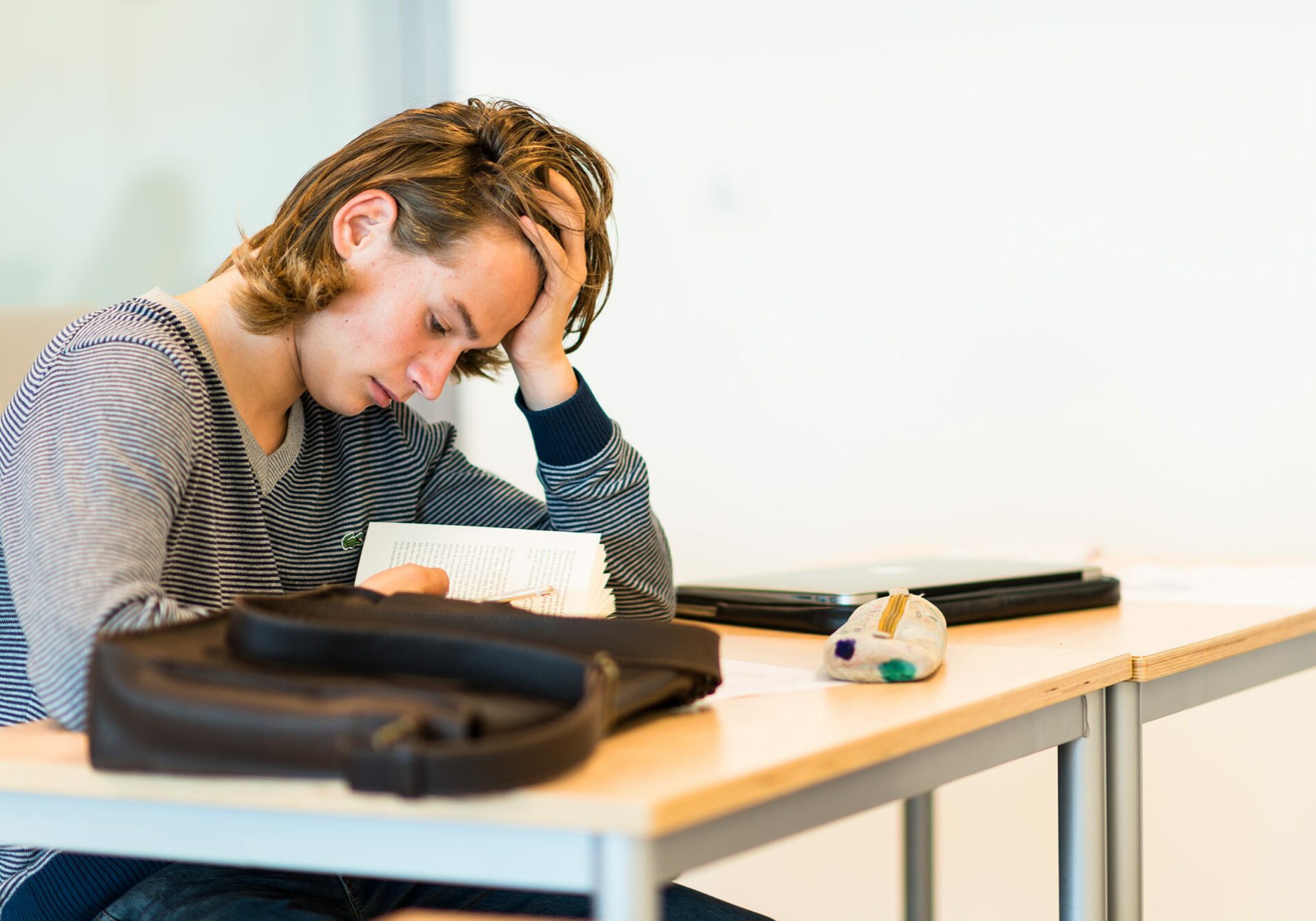 Gutt på vgs som sitter ved pult og leser
