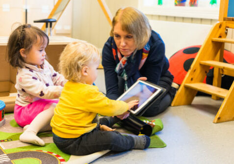 Barnehagebarn og voksen med iPad