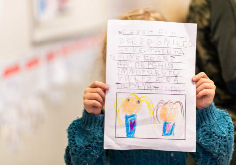 Jente viser brev på barneskole / begynneropplæring